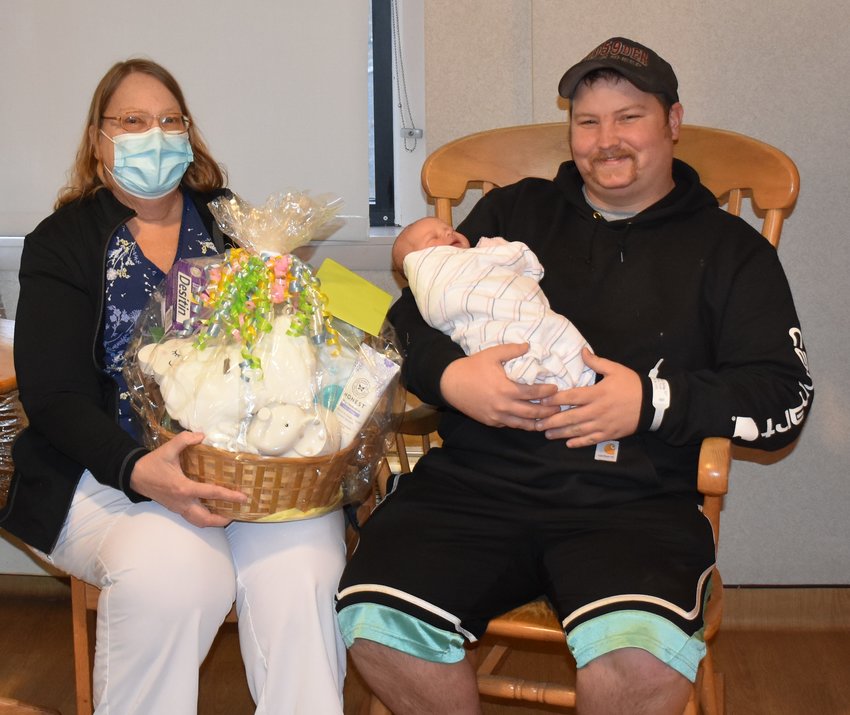 Dixie Lynn Reese, first baby of 2022, is held by her dad, Austin. Joyce Bannon, RN, holds a gift basket from the New Beginnings staff.